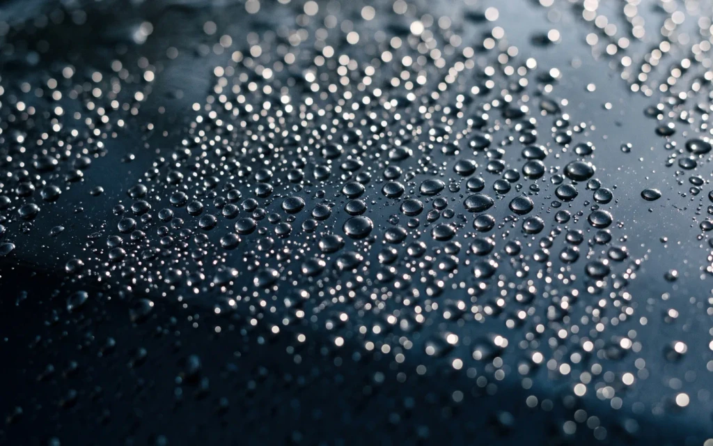 Water beads on dark navy paint, close up